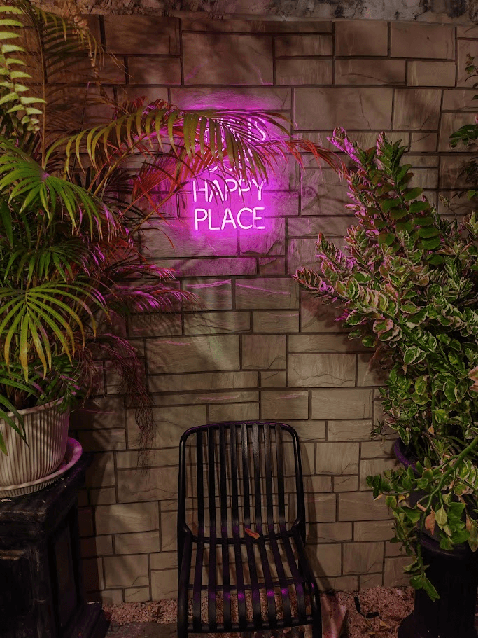 Pink neon Happy Place sign in the courtyard